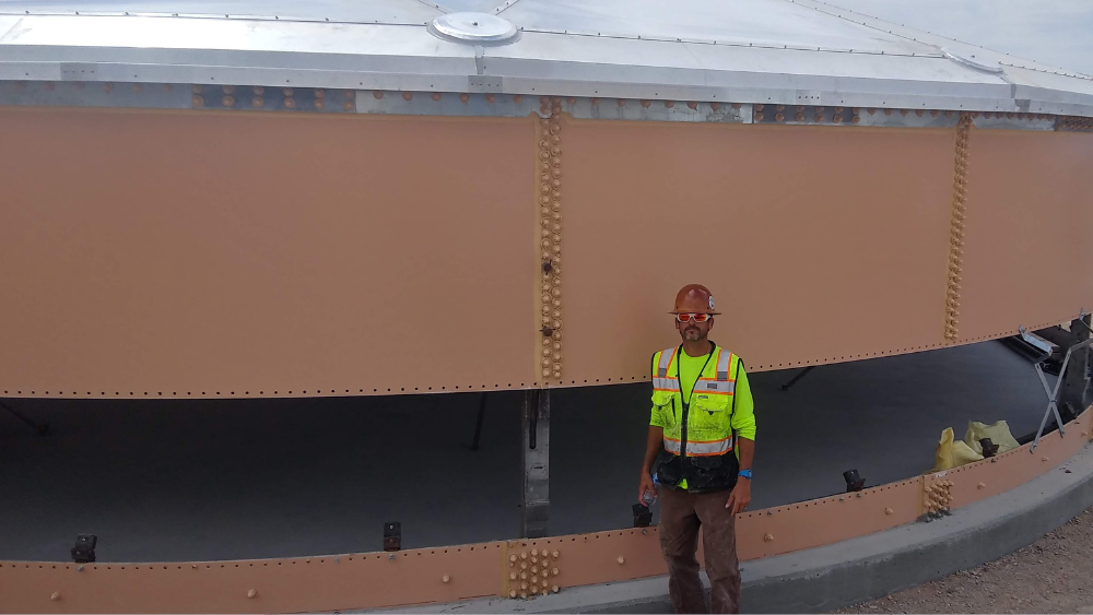 Jason Miller standing in front of a partially assembled bolted steel tank